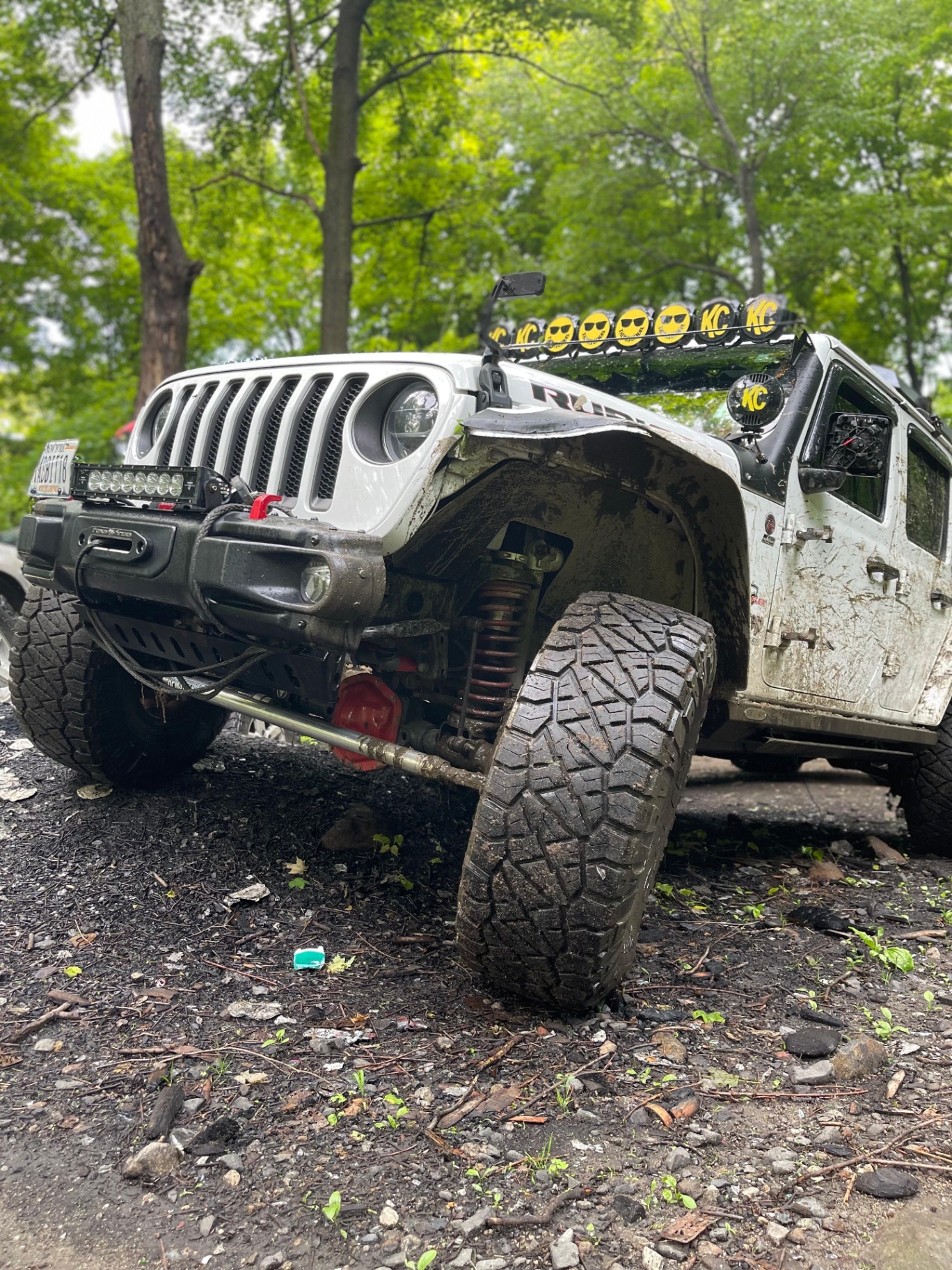 Muddy white Jeep Rubicon with KC light bar after a run