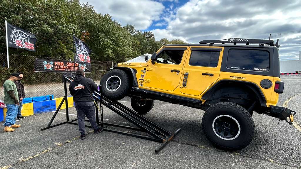 Lifted yellow Jeep Wrangler on Fab-Shop ramp at an event