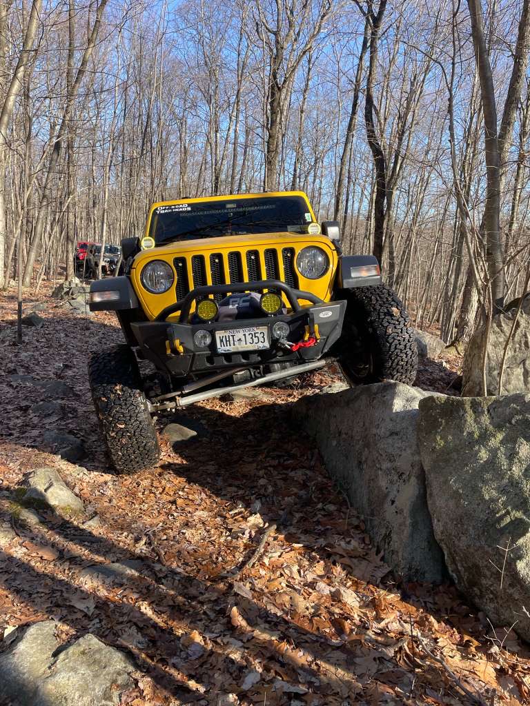 Yellow Wrangler crawling rocks in the woods