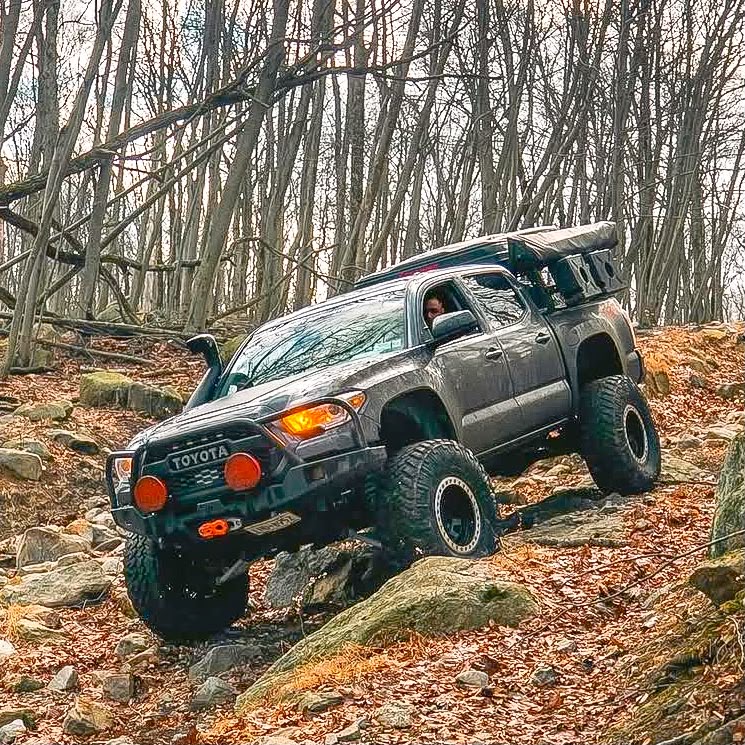 Tacoma with snorkel and roof tent climbing rocky New York trail
