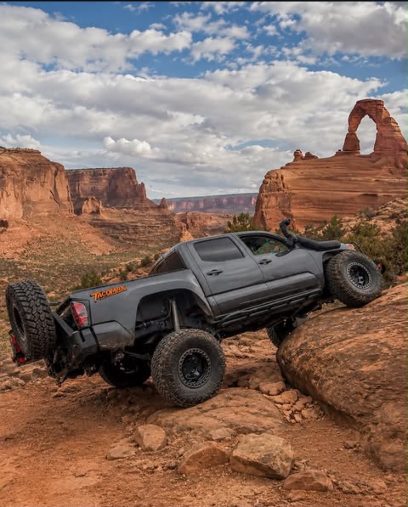 Lifted Toyota Tacoma flexing on slickrock near Delicate Arch